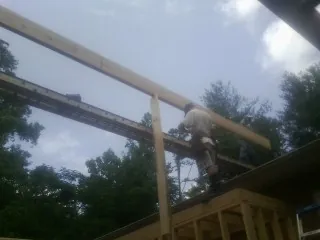 Carpenter setting a ridge beam over a new addition frame — Ice Dam Removal by Roofing Brothers in Elysburg