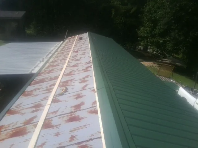 Old rusted panels beside newly installed green metal roofing — Wind Damage Roof Repair by Roofing Brothers in Elysburg