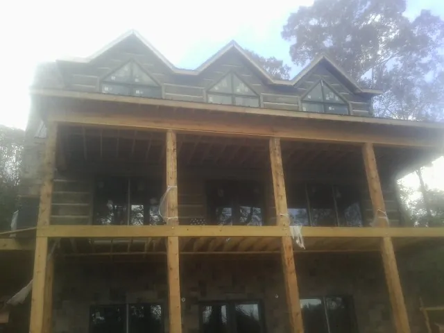 Dormers and porch framing on a large log home under construction — Roof Coating work by our crew in Elysburg