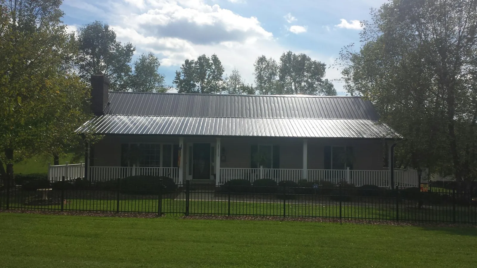 Gray metal roof on a brick ranch with a full width front porch — Gutter Guard Installation work by our crew in Elysburg