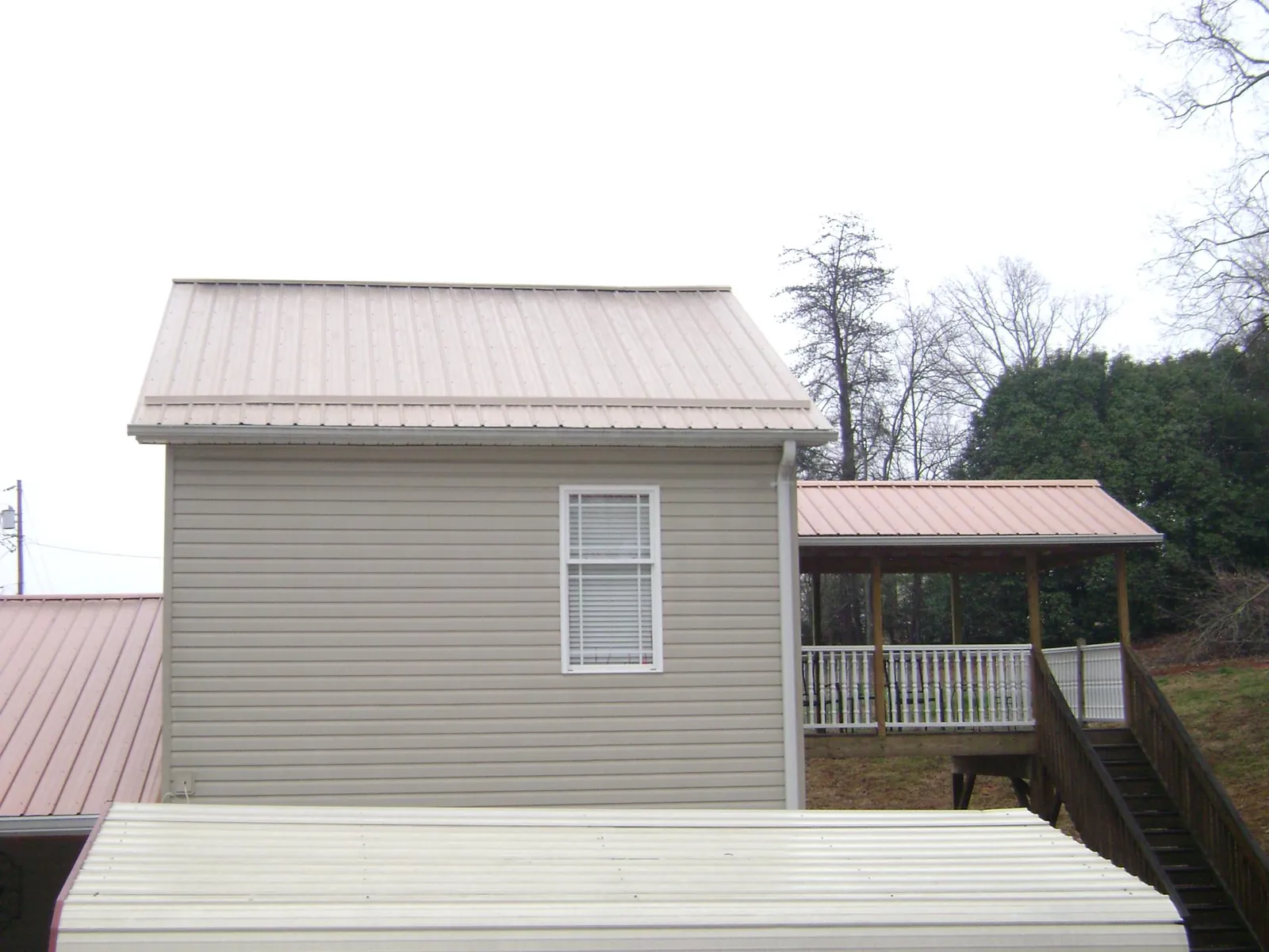 Tan metal roofs on a two story addition and attached porch, from a Roof Replacement job in Elysburg