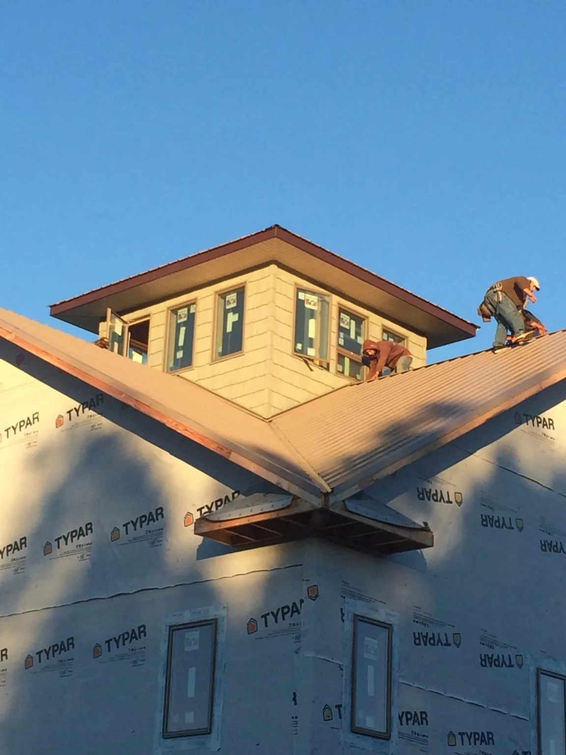 Roofers working around a rooftop cupola on a new metal roof at sunset — Roof Waterproofing in Elysburg by Roofing Brothers